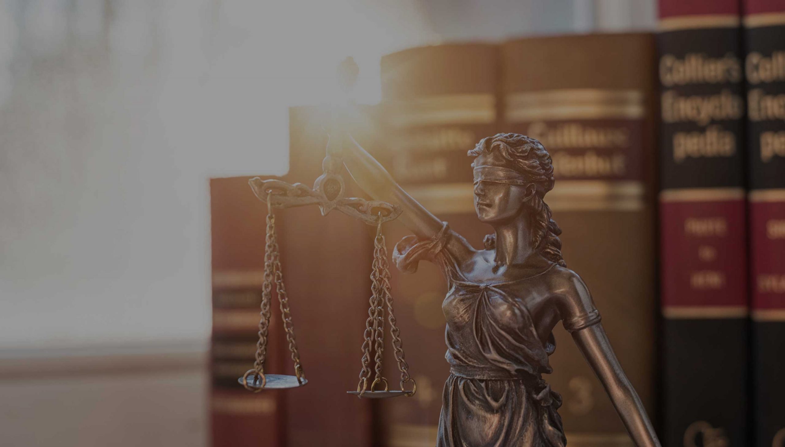 Μεταλλικό άγαλμα της Θέμιδος και στο βάθος βιβλία