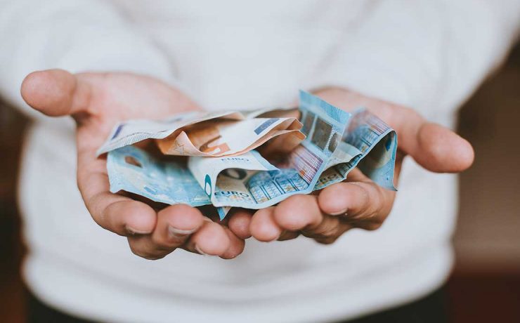 χαρτονομίσματα του ευρώ πάνω σε δύο ανοιχτά χέρια