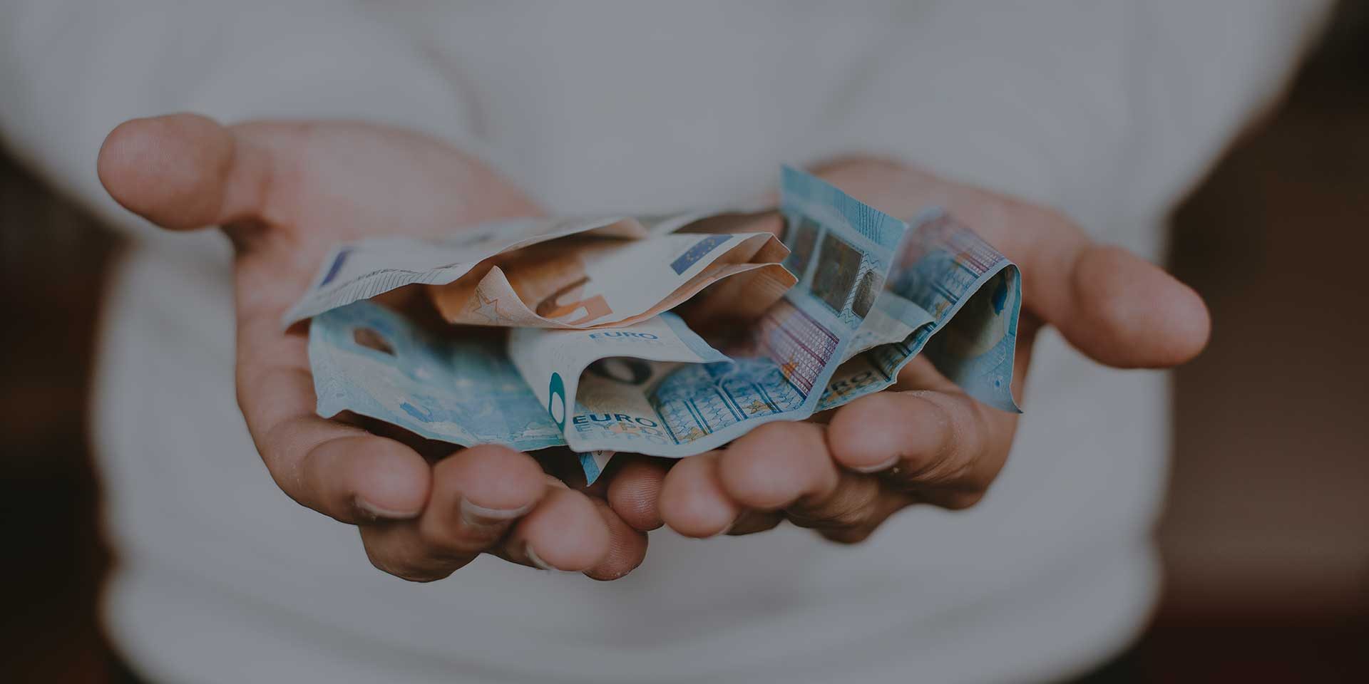 χαρτονομίσματα του ευρώ πάνω σε δύο ανοιχτά χέρια