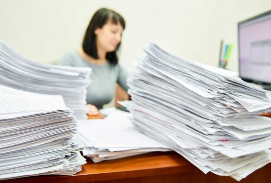 Γυναίκα δημόσιος υπάλληλος σε γραφείο γεμάτο έγγραφα