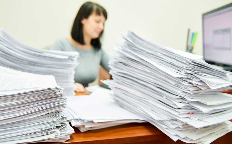 Γυναίκα δημόσιος υπάλληλος σε γραφείο γεμάτο έγγραφα