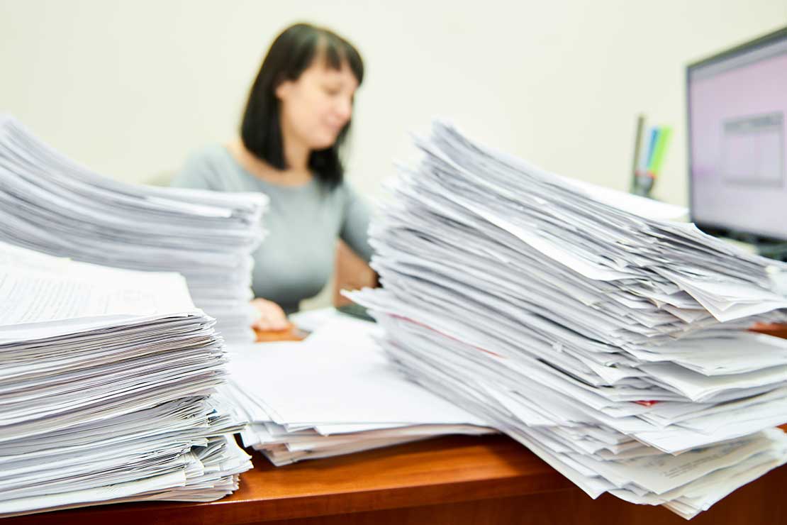 Γυναίκα δημόσιος υπάλληλος σε γραφείο γεμάτο έγγραφα