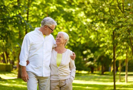 Ζευγάρι ηλικιωμένων περπατάει αγκαλιασμένο σε πάρκο